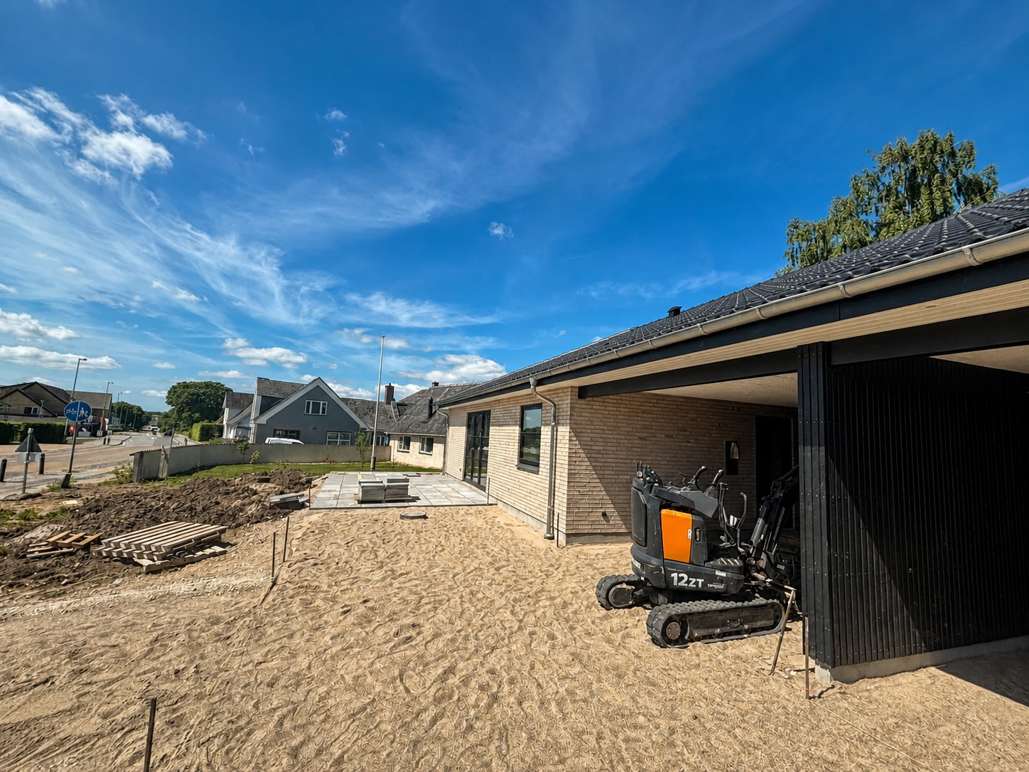 Nyt lejemål med lys mursten, sort carport og blå himmel
